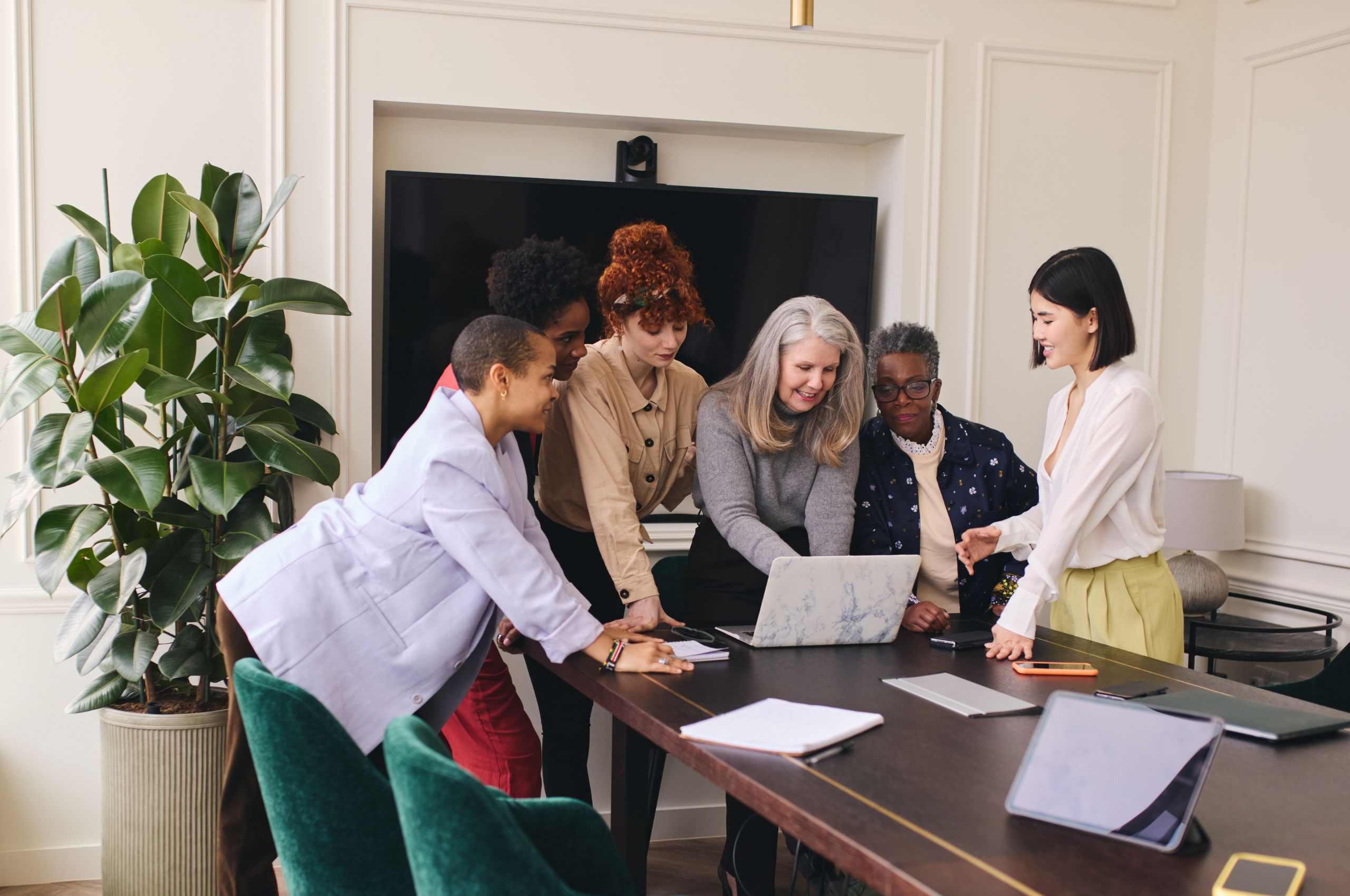 Women of various ages and ethnicities having a meeting around a laptop