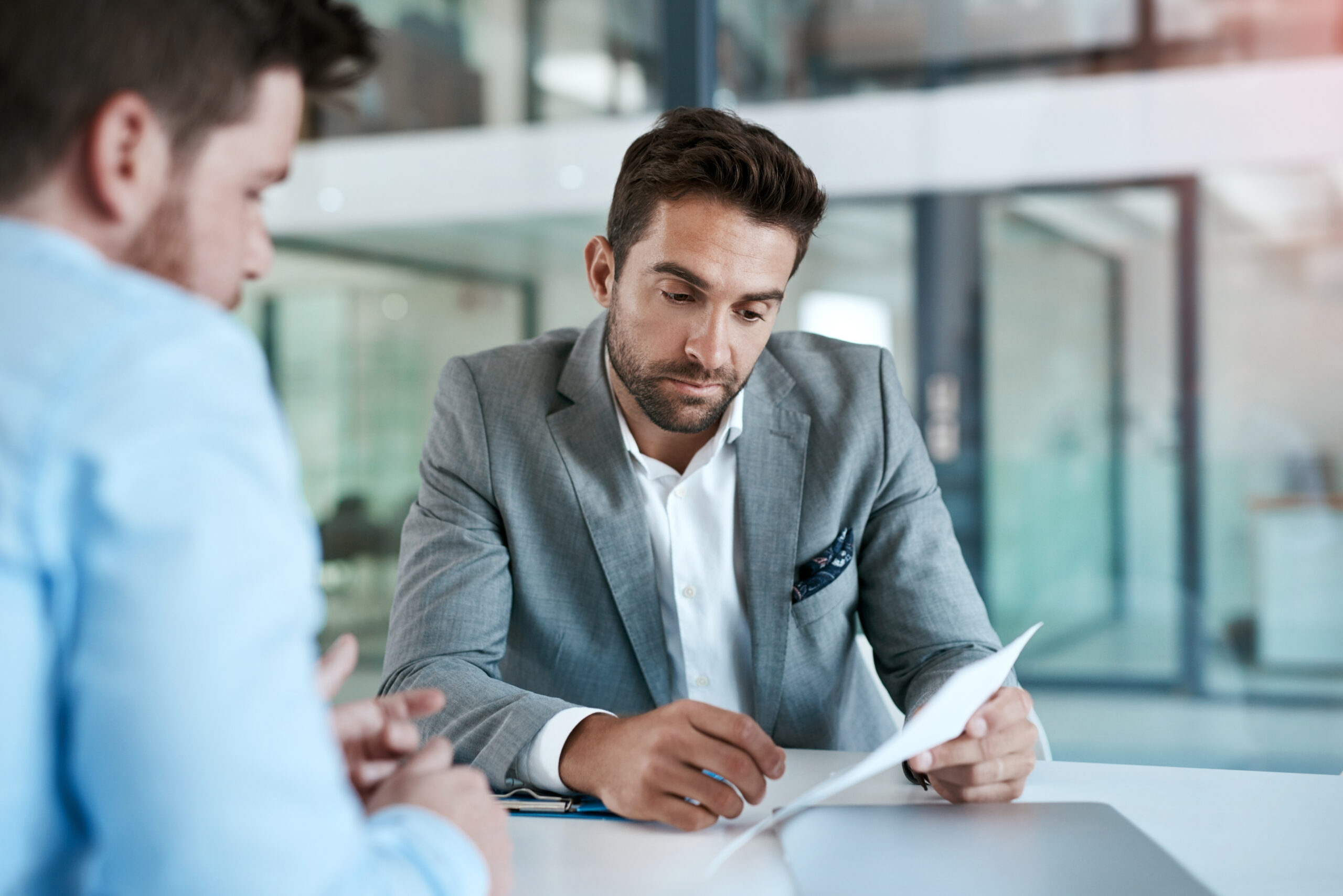 Two men in suits looking at figures on a piece of paper