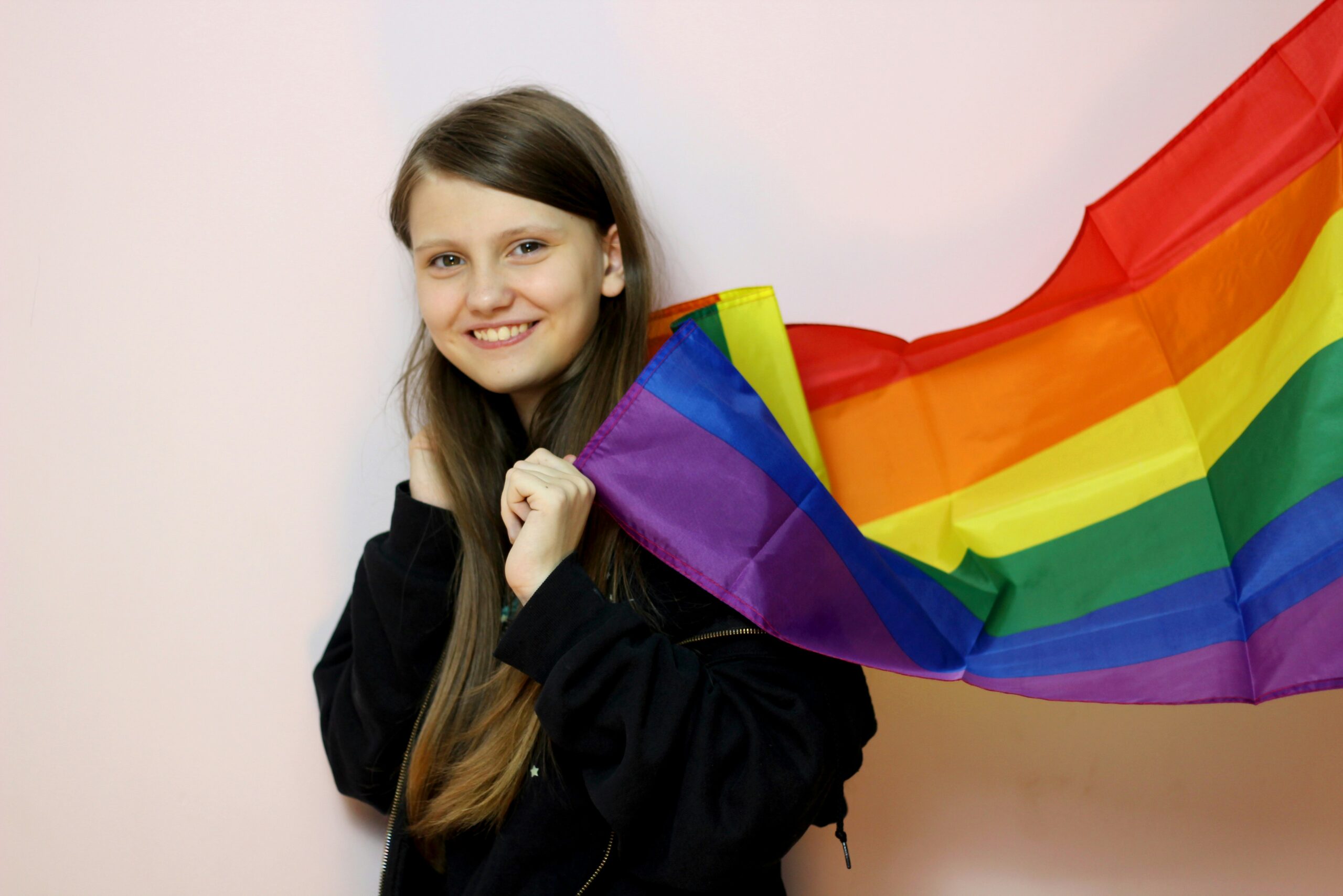 A young person wearing a pride flag as a cape