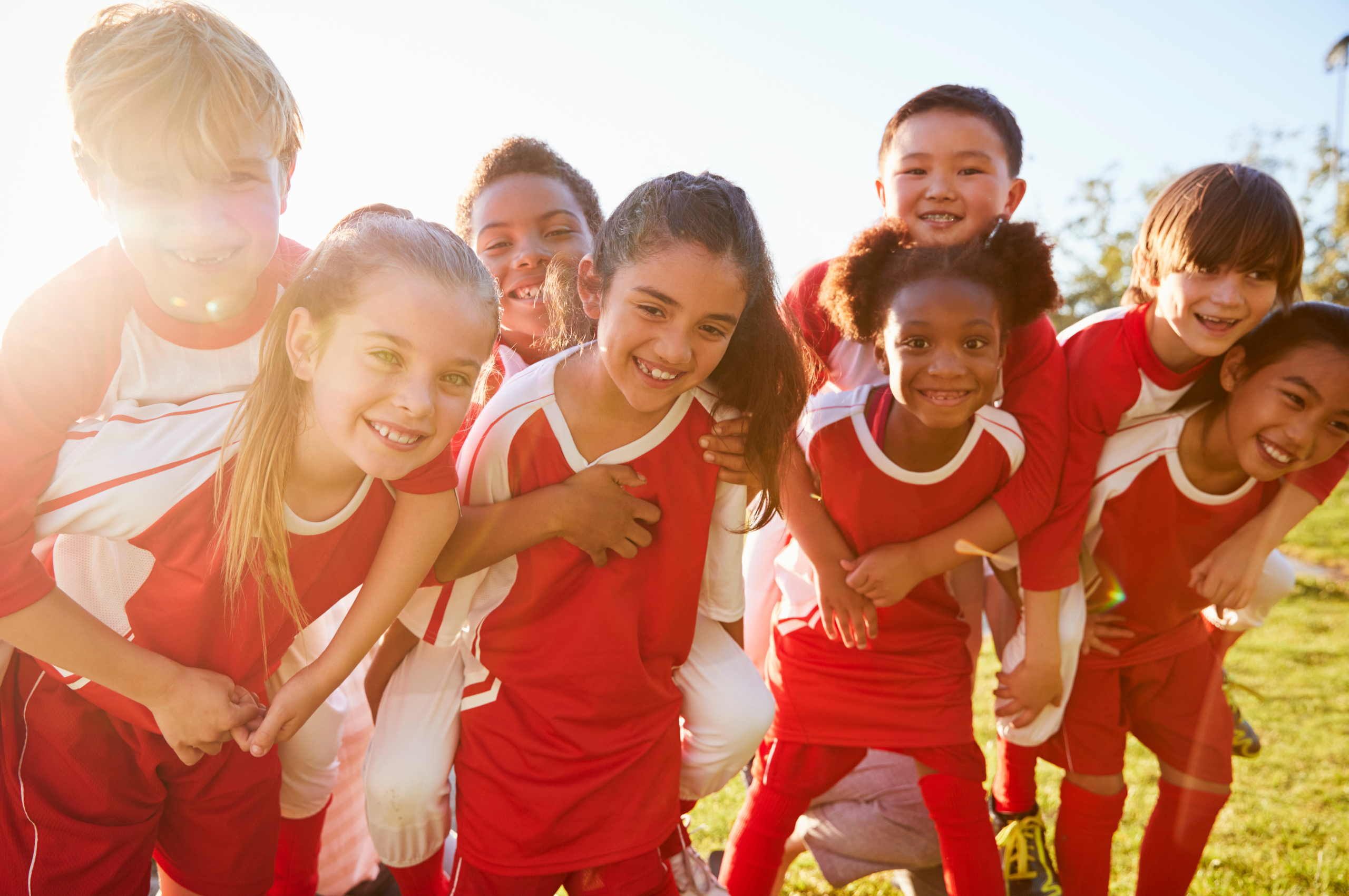a group of children pose for a picture in their red football kit.